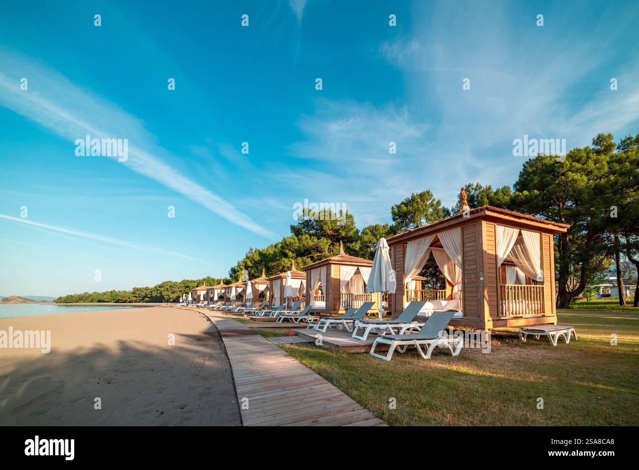Private Strandhütten an einer ruhigen Sandküste bei Sonnenuntergang Stockfoto