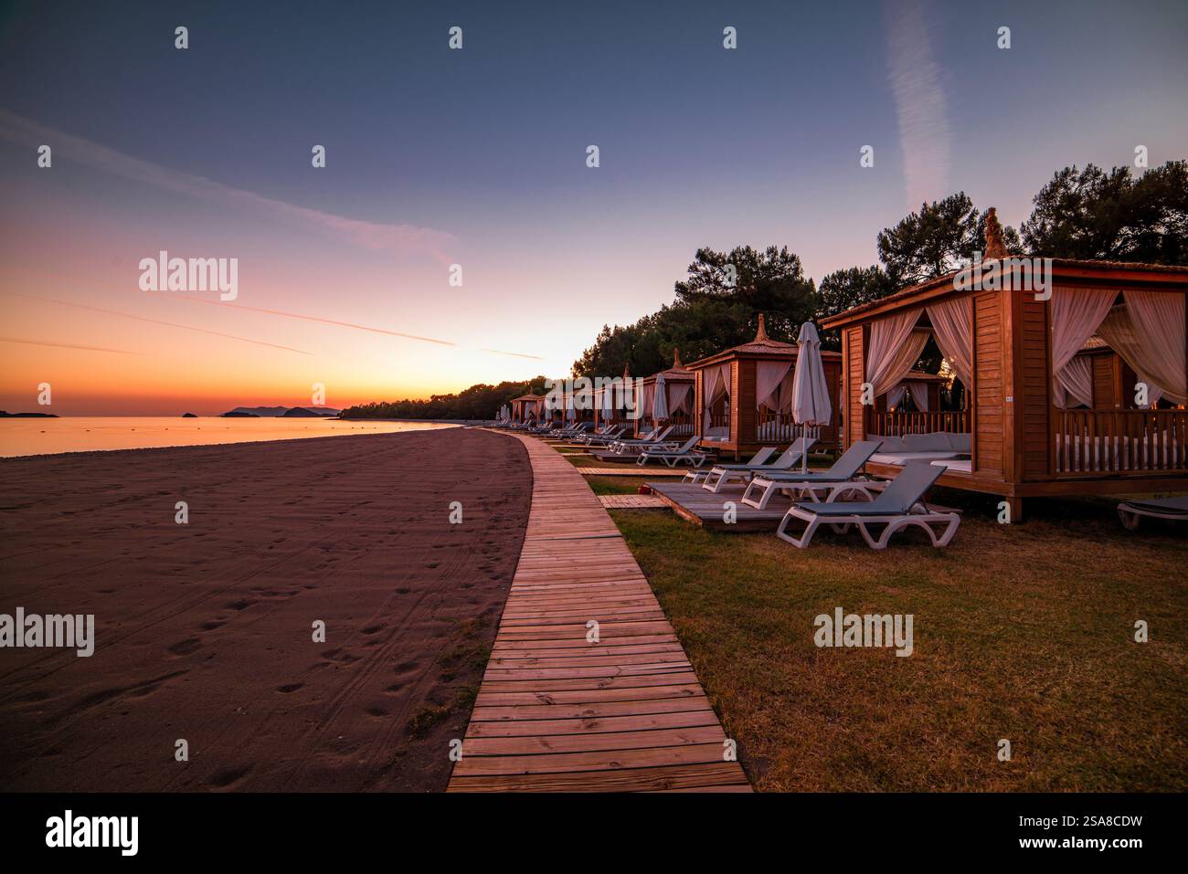Private Strandhütten an einer ruhigen Sandküste bei Sonnenuntergang Stockfoto