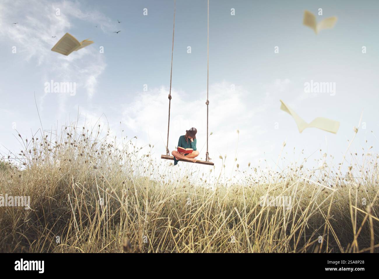 Eine Frau auf einer Schaukel, die am Himmel hängt, liest ein Buch, umgeben von fliegenden Seiten, die wie Vögel aussehen Stockfoto
