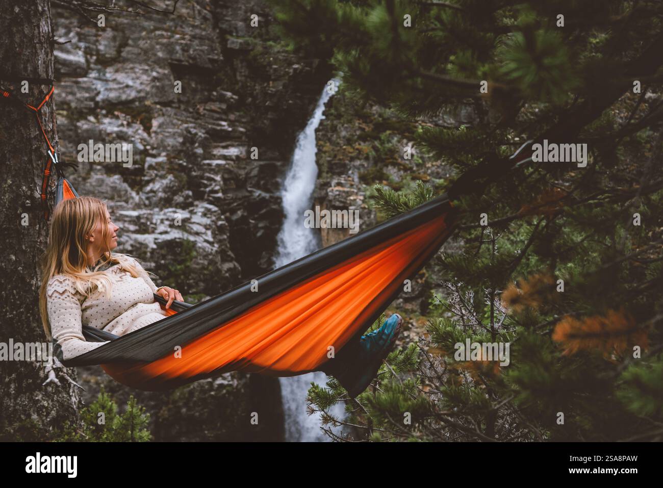 Sommerurlaub - Frau chillt in Hängematte in Wald Reise Outdoor Tourist Mädchen genießen Wasserfall Ansicht in Norwegen Abenteuer Reise gesunde Lebensweise Stockfoto