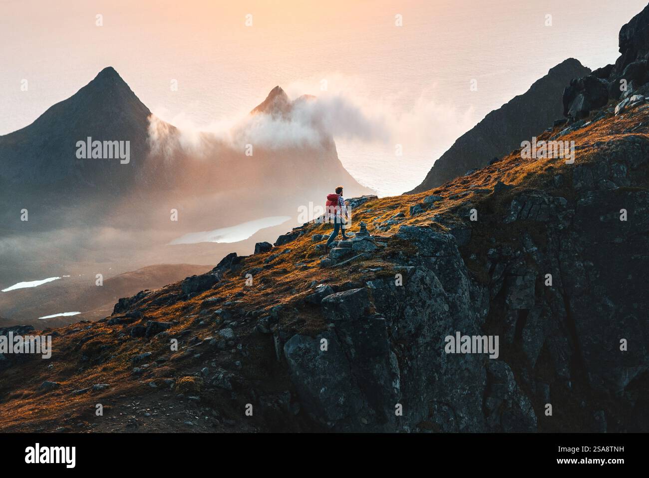 Mann kletternd Berge Reisen in Norwegen Touristen allein Wandern in Lofoten Inseln Outdoor Reisende mit Rucksack aktiv gesunde Lebensstil Abenteuer su Stockfoto