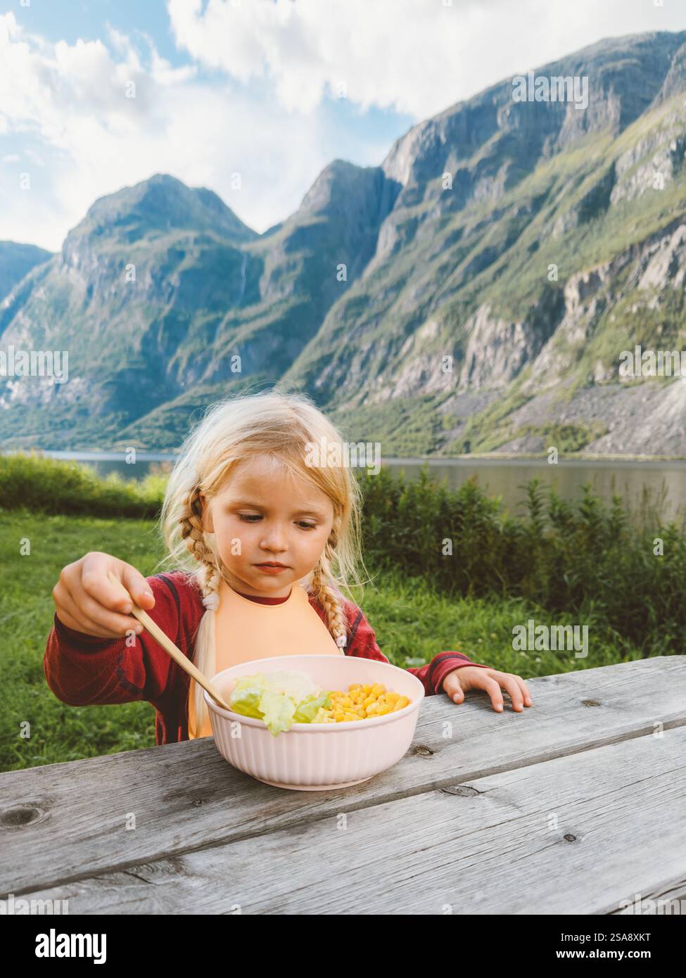 Sommer-Picknick in Norwegen - Kind Mädchen isst veganes Essen Salat Outdoor Familienreisen Urlaub Lifestyle, 4 Jahre altes Kind hat gesundes Frühstück mit Stockfoto