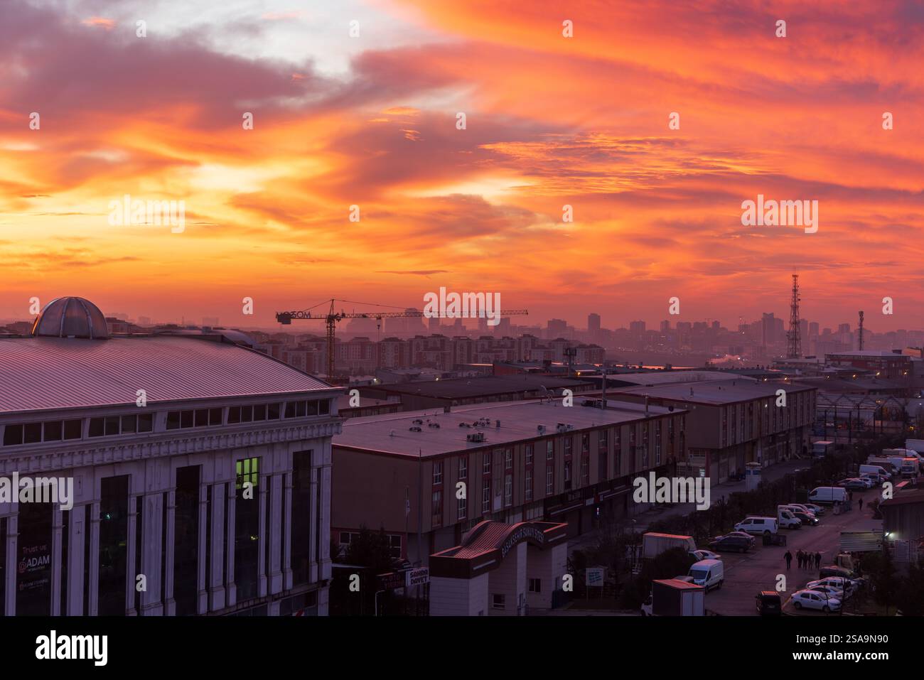 Skyline von Istanbul Basaksehir bei Sonnenuntergang mit leuchtenden orange und roten Wolken. Städtische Landschaft mit Industriegebäuden Stockfoto