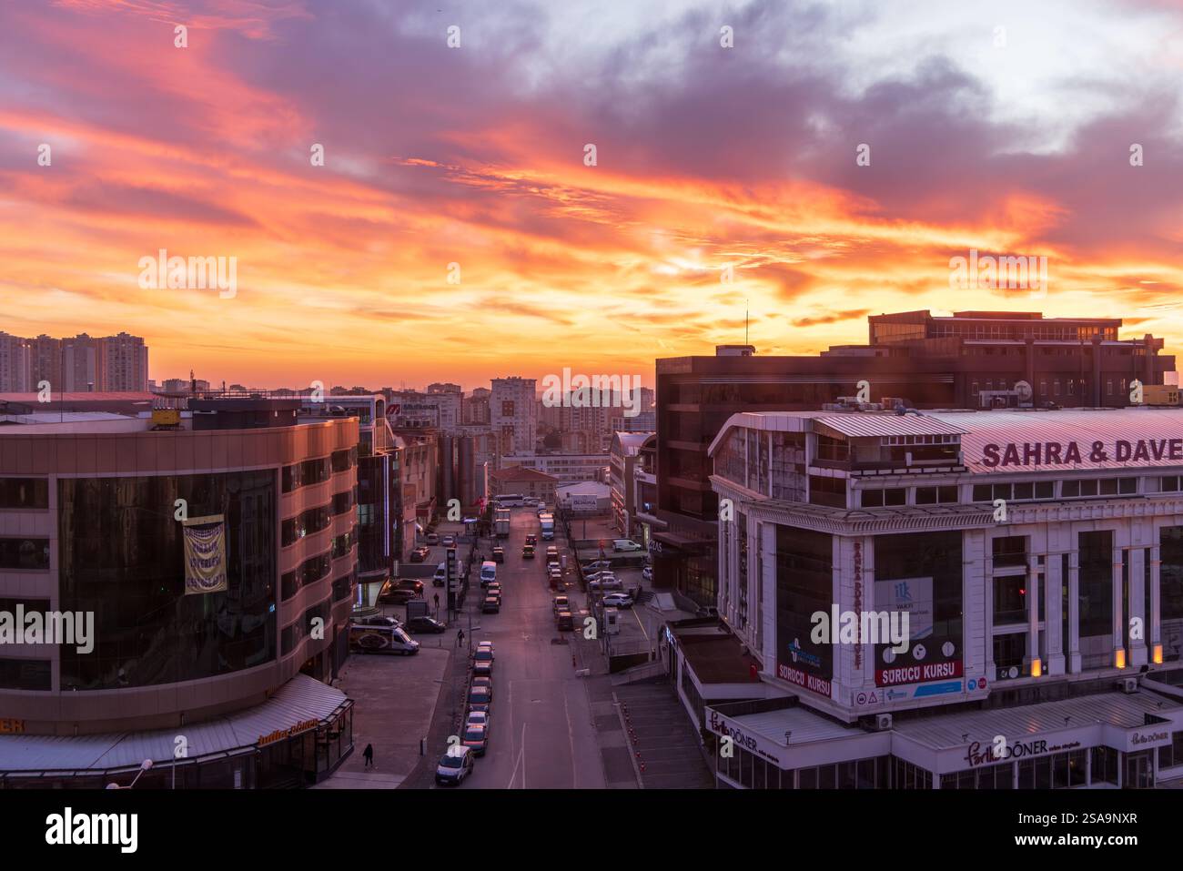Skyline von Istanbul Basaksehir bei Sonnenuntergang mit leuchtenden orange und roten Wolken. Städtische Landschaft mit Industriegebäuden Stockfoto