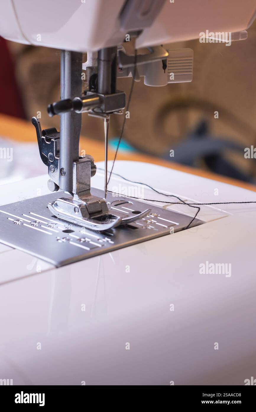 Eine Nahaufnahme einer Nähmaschine, die Nadel, Nähfuß und Fadenmechanismus aufwändig betont Stockfoto