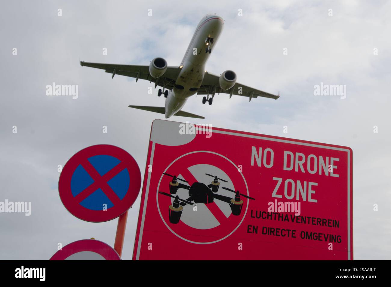 Hochfliegender Widerspruch: Das Flugzeug überquert das Schild „No Drone Zone“ mit niederländischer Warnung Stockfoto