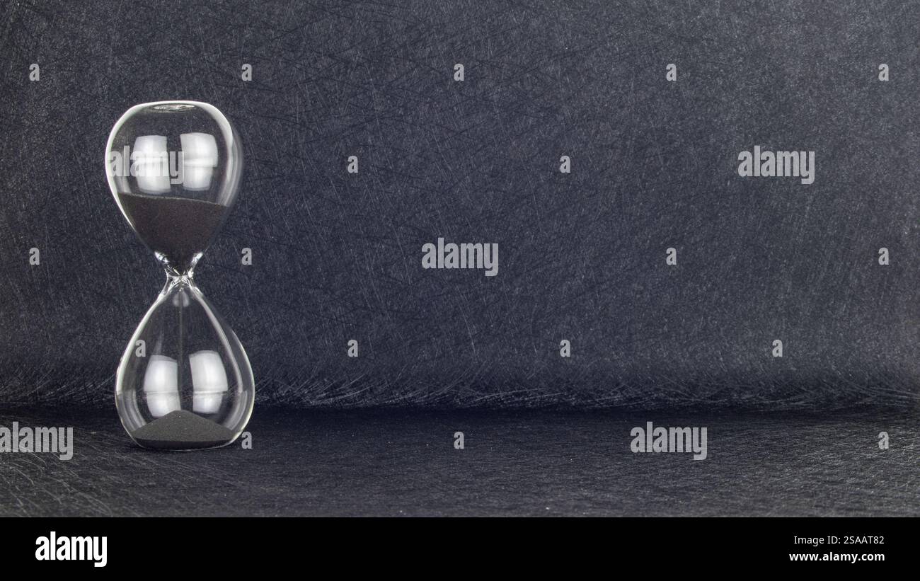 Schwarze Sanduhr sandglas schwarzer Hintergrund. Eieruhr aus Sandglas. Die Zeit fliegt im Zeitverlauf. Termin nähert sich. Die Zeit wird knapp Stockfoto