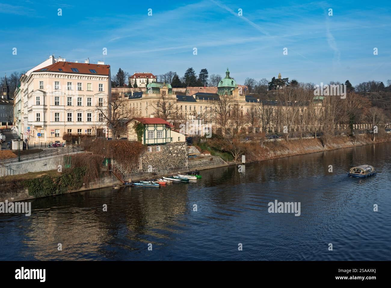 Linkes Ufer der Moldau in Prag mit der Mautstelle der ehemaligen Hängebrücke „Rudolfova lávka“ und dem Komplex „Strakova Akademie“, Regierungssitz. Stockfoto