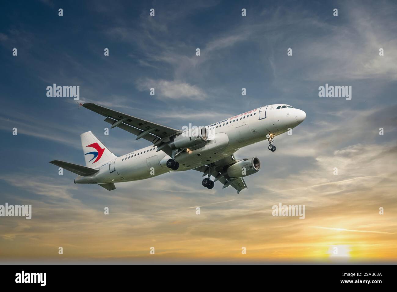 China Eastern Airline A319 Passagierflugzeug fliegt am Himmel. Das Flugzeug gegen den Sonnenuntergang bereitet sich auf die Landung auf dem Flughafen vor. Reisefoto, Stockfoto