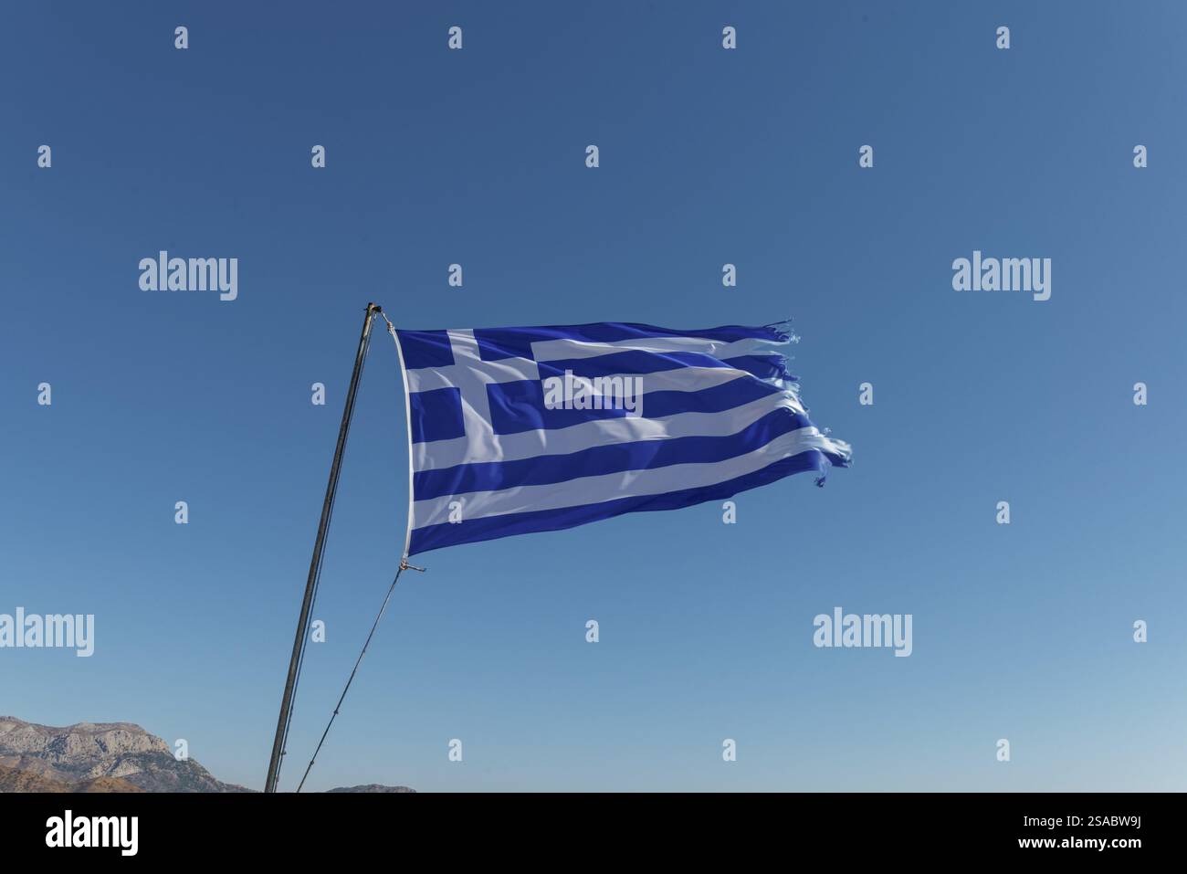 Griechische Flagge winkt im Wind vor einem klaren blauen Himmel, Menetes, Karpathos, Griechenland, Europa Stockfoto