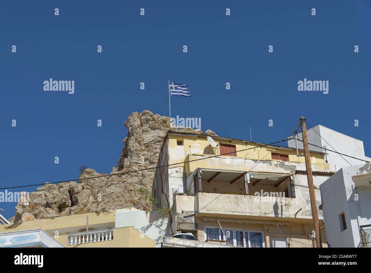Gebaut auf einem Felsen mit griechischer Flagge unter klarem Himmel, Karpathos Town, Karpathos, Griechenland, Europa Stockfoto