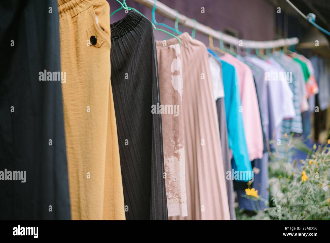 Bunte Kleidung hängt an einer Wäscheleine, um draußen zu trocknen. Stockfoto