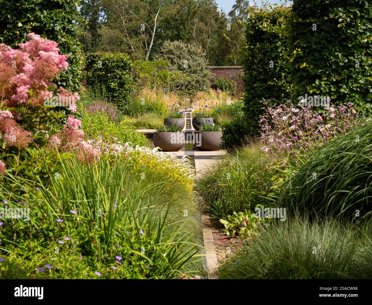 Zentraler Rang mit großen dekorativen Töpfen auf beiden Seiten im ruhigen Paradise Garden am RHS Bridgewater. Stockfoto