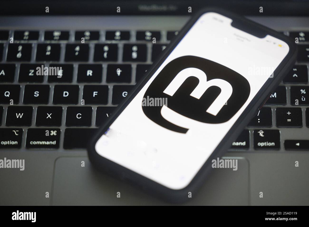 Logo von Mastodon, einem neuen Social-Networking-Dienst hier auf einem Mobiltelefon über der Tastatur eines Computers Stockfoto