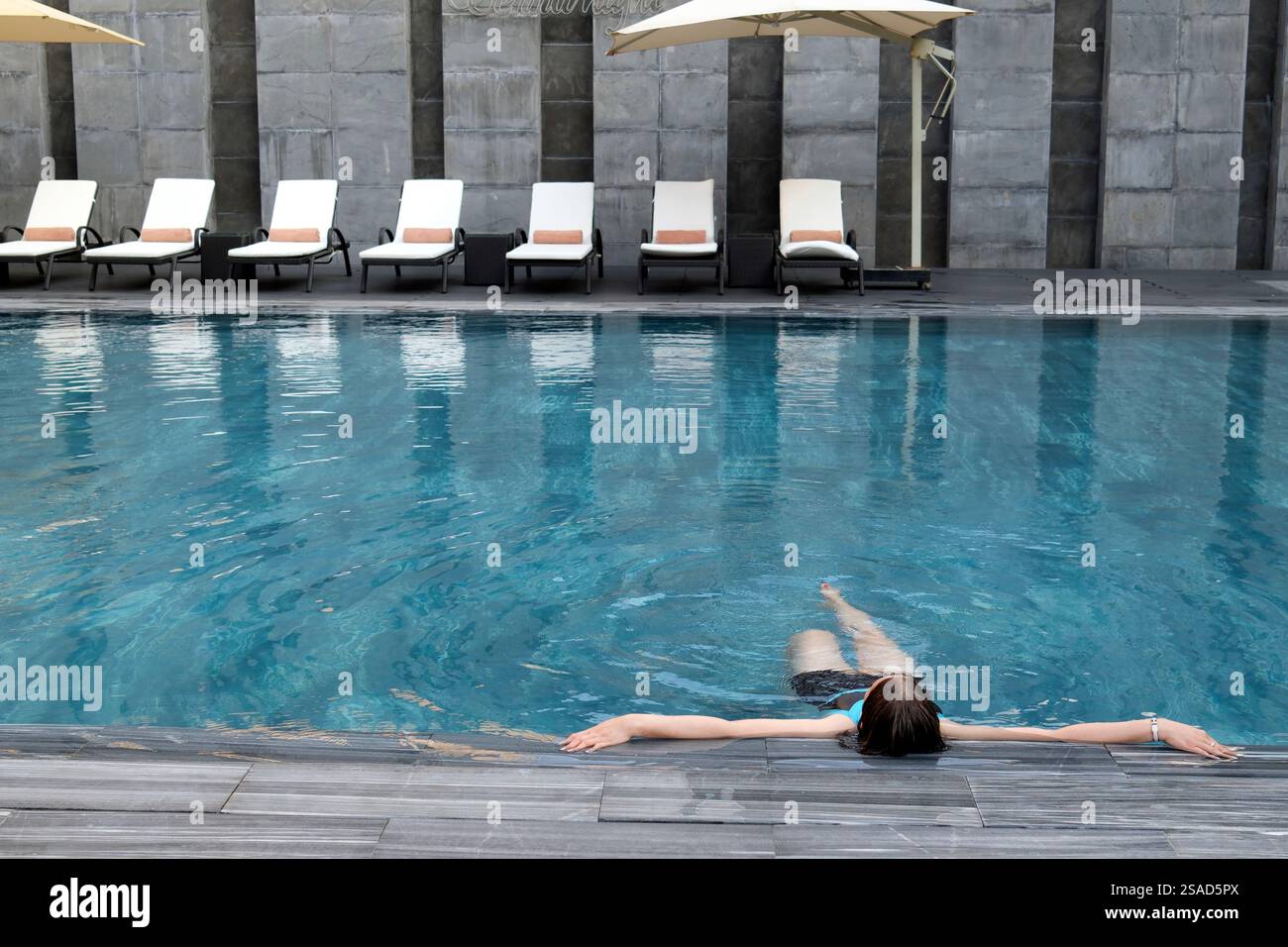 Swimmingpool in einem Luxushotel. Frau im Urlaub, die das Wasser genießt. Farbton. Vietnam. Stockfoto Swimmingpool in einem Luxushotel. Frau im Urlaub, die das Wasser genießt. Farbton. Vietnam. Stockfoto