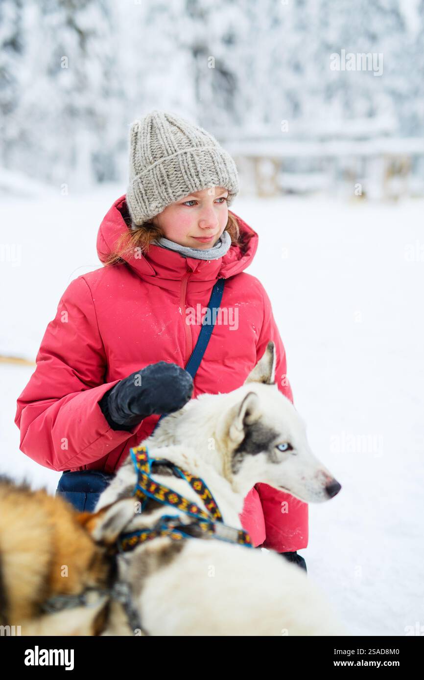Entzückendes Mädchen vor Teenagern, das draußen mit Husky-Hunden kuschelt, am Wintertag in Lappland Finnland Stockfoto