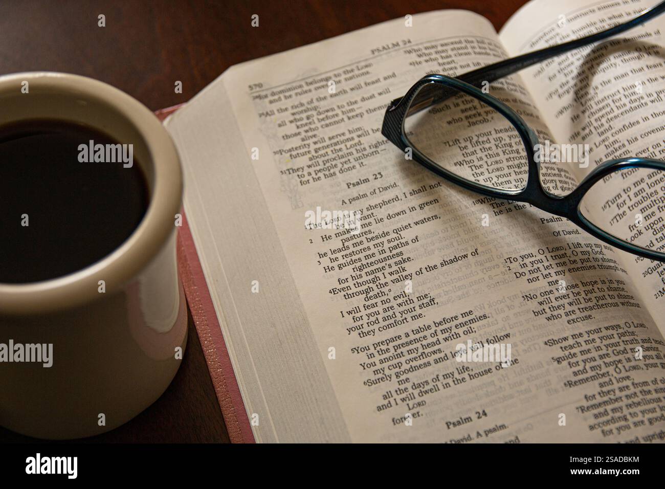 Morgendämmerung. Bibel offen für Psalm 23 mit Lesebläsern und einer Tasse Kaffee. Stockfoto