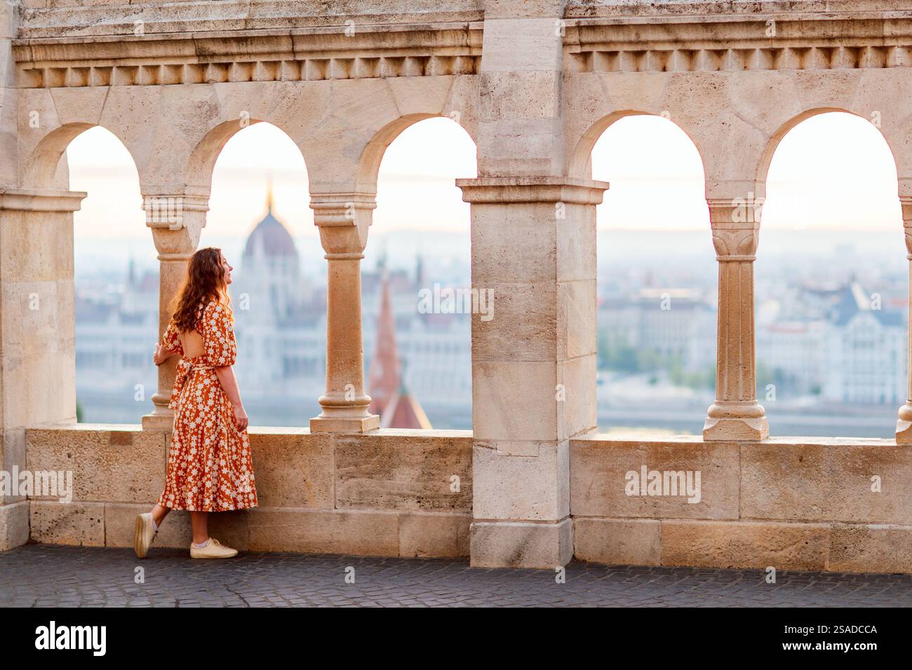 Rückansicht der kaukasischen Frau, die morgens von der Fischerbastei aus den Blick über das Parlament in Budapest genießt Stockfoto