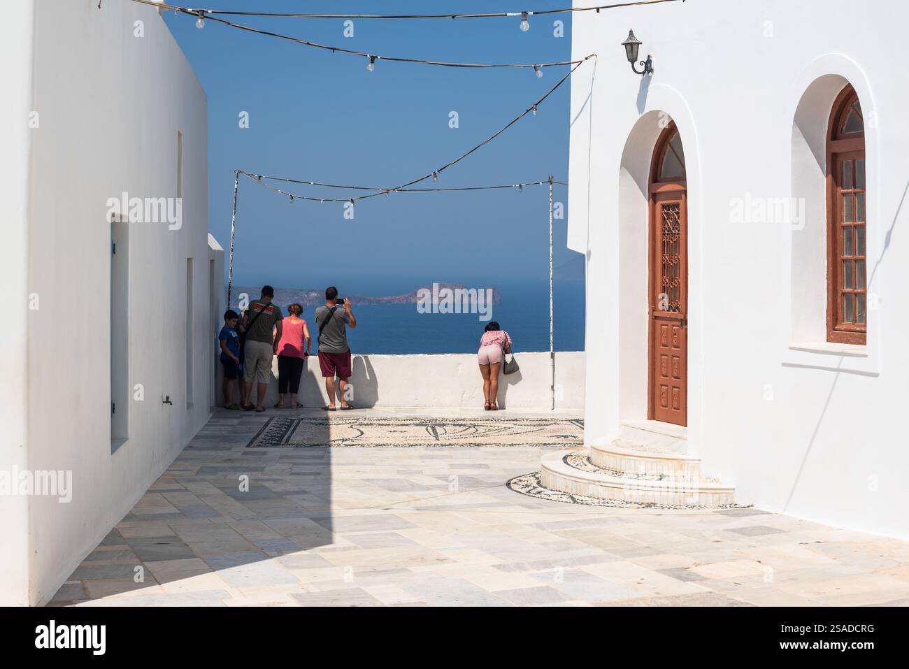 Touristen mit Blick auf den See und den Horizont in der Kirche Panagia Korphiatissa im Dorf Plaka. Insel Milos, Griechenland. Stockfoto