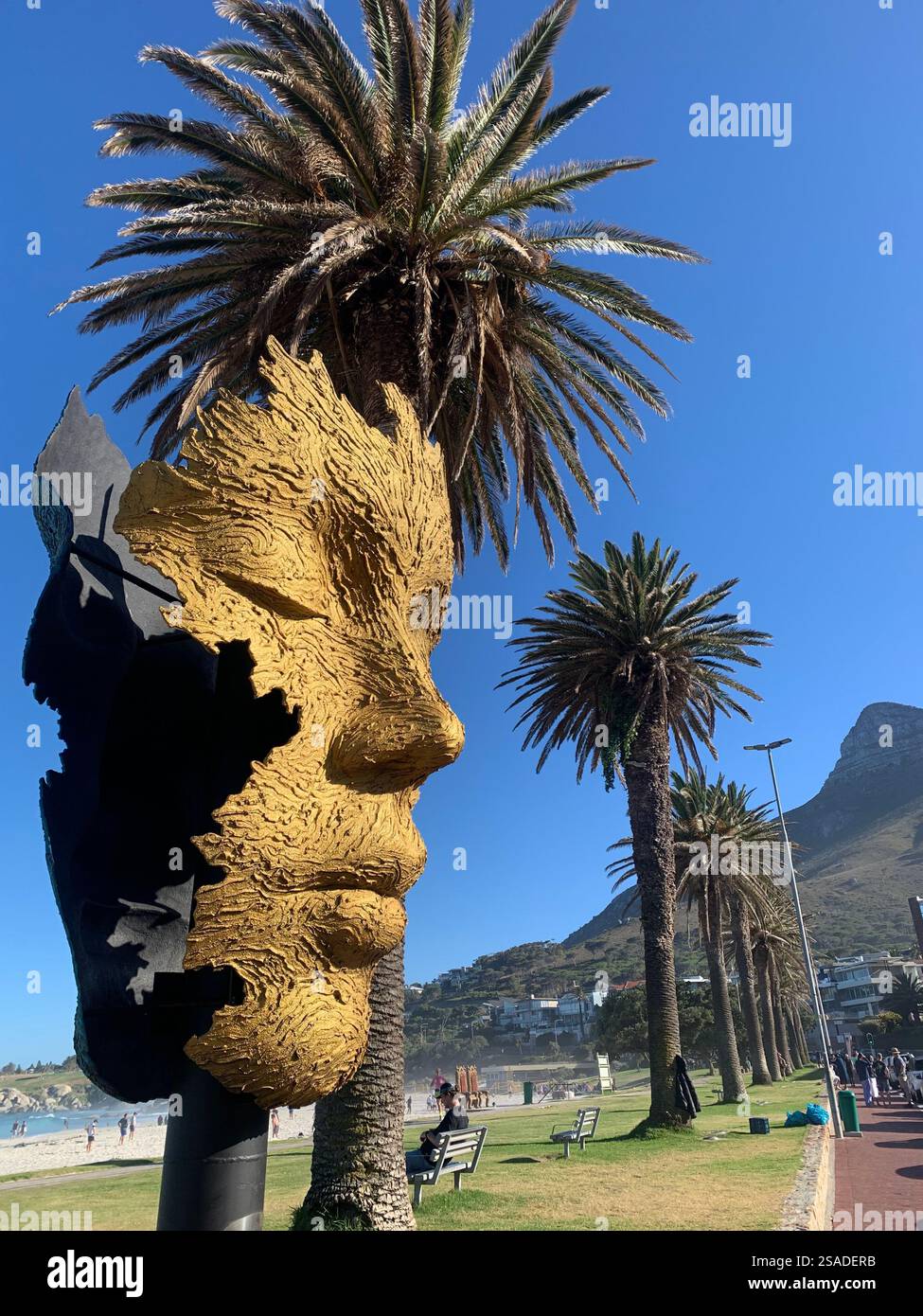 goldene Gesichtsskulptur mit geschlossenen Augen mit Palmenhaaren Stockfoto