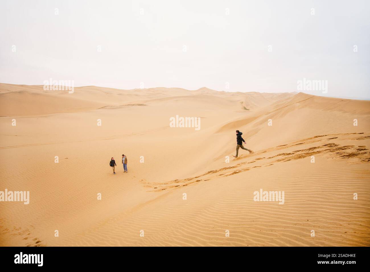 Familie mit Mutter und Kindern, die Spaß beim Ablaufen von der Sanddüne des Sandwich Harbour in Namibia haben Stockfoto