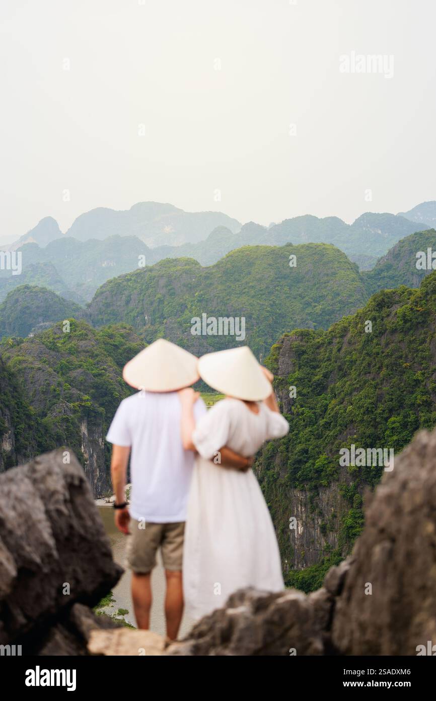 Ein wunderschönes Paar reist gerne durch Südostasien und betrachtet die Aussicht auf die Karstberge und den Fluss der Mua Cave in Vietnam. Konzentrieren Sie sich auf die atemberaubende Stockfoto