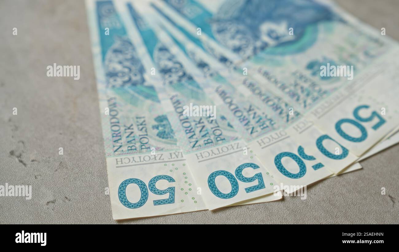 Polnische Banknoten im Wert von 50 Zloty sind auf einer Betonoberfläche mit verschiedenen Stückelungen verteilt. Stockfoto