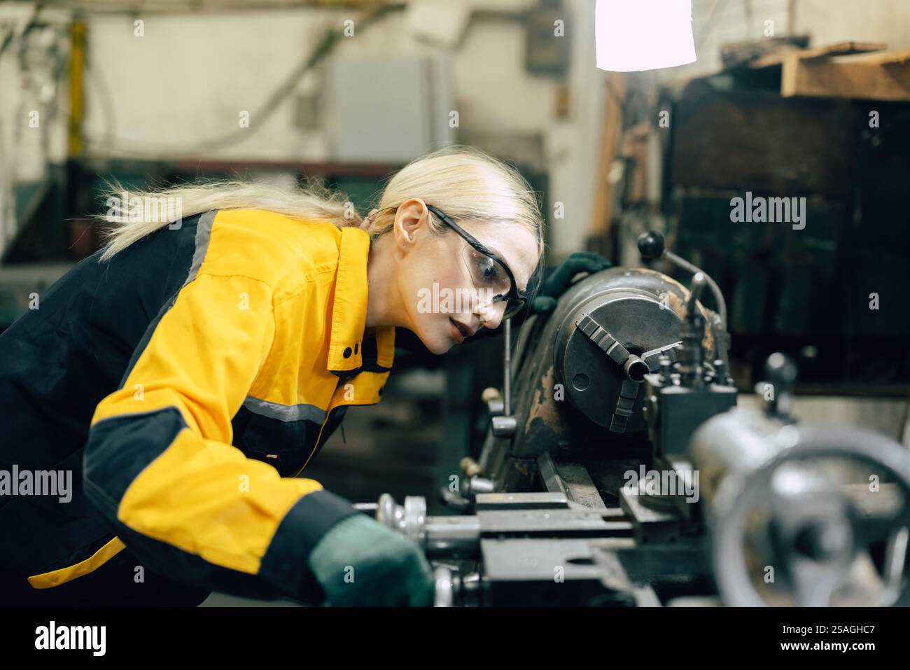 kaukasische Frauen arbeiten in einer Fabrik der Schwermetallindustrie mit einer Drehmaschine aus Stahl Stockfoto