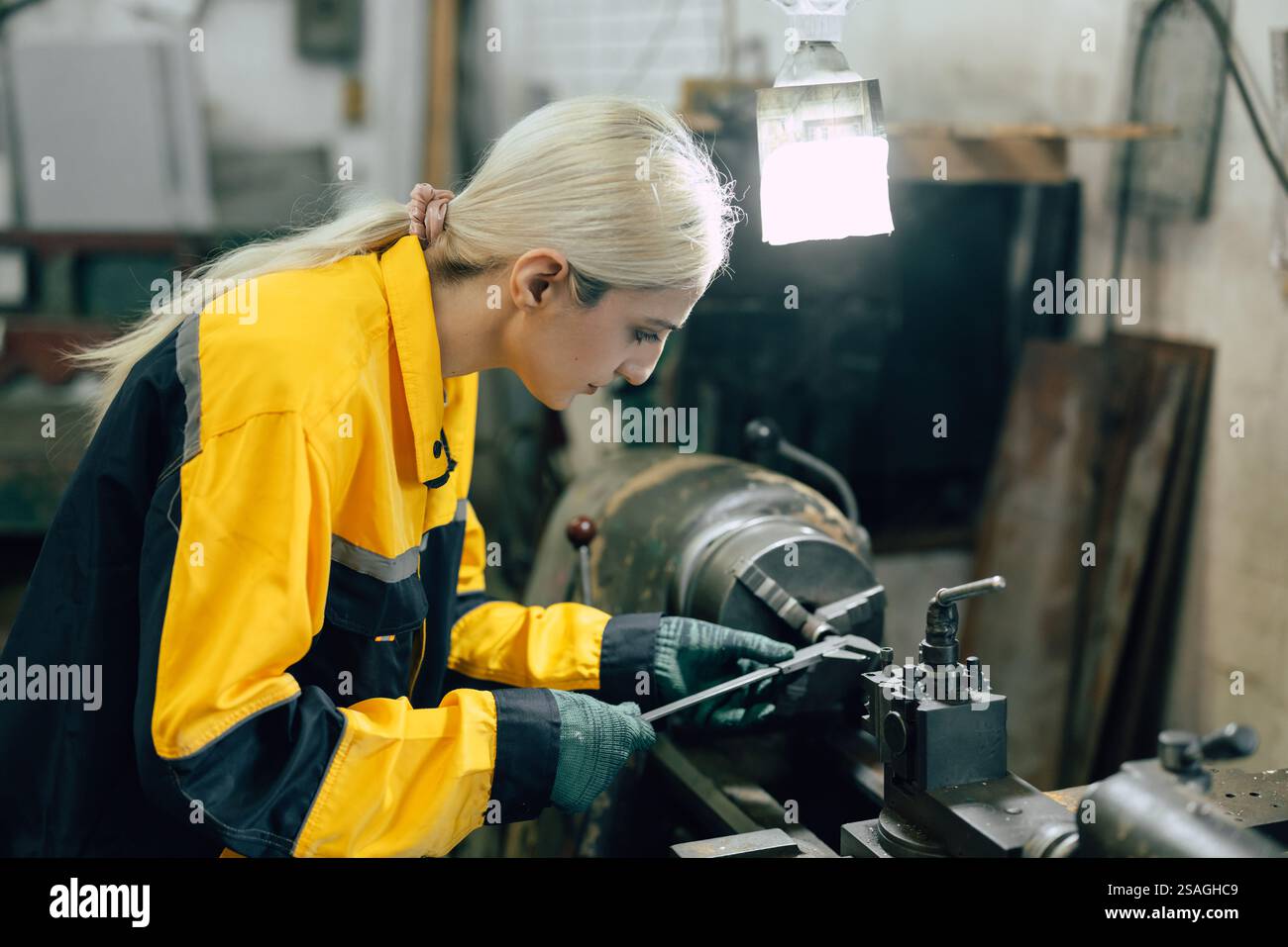 Arbeitnehmerin mit Messschieber zum Messen von Metallteilen in Drehmaschinen in der Schwermetallwerkstatt Stockfoto