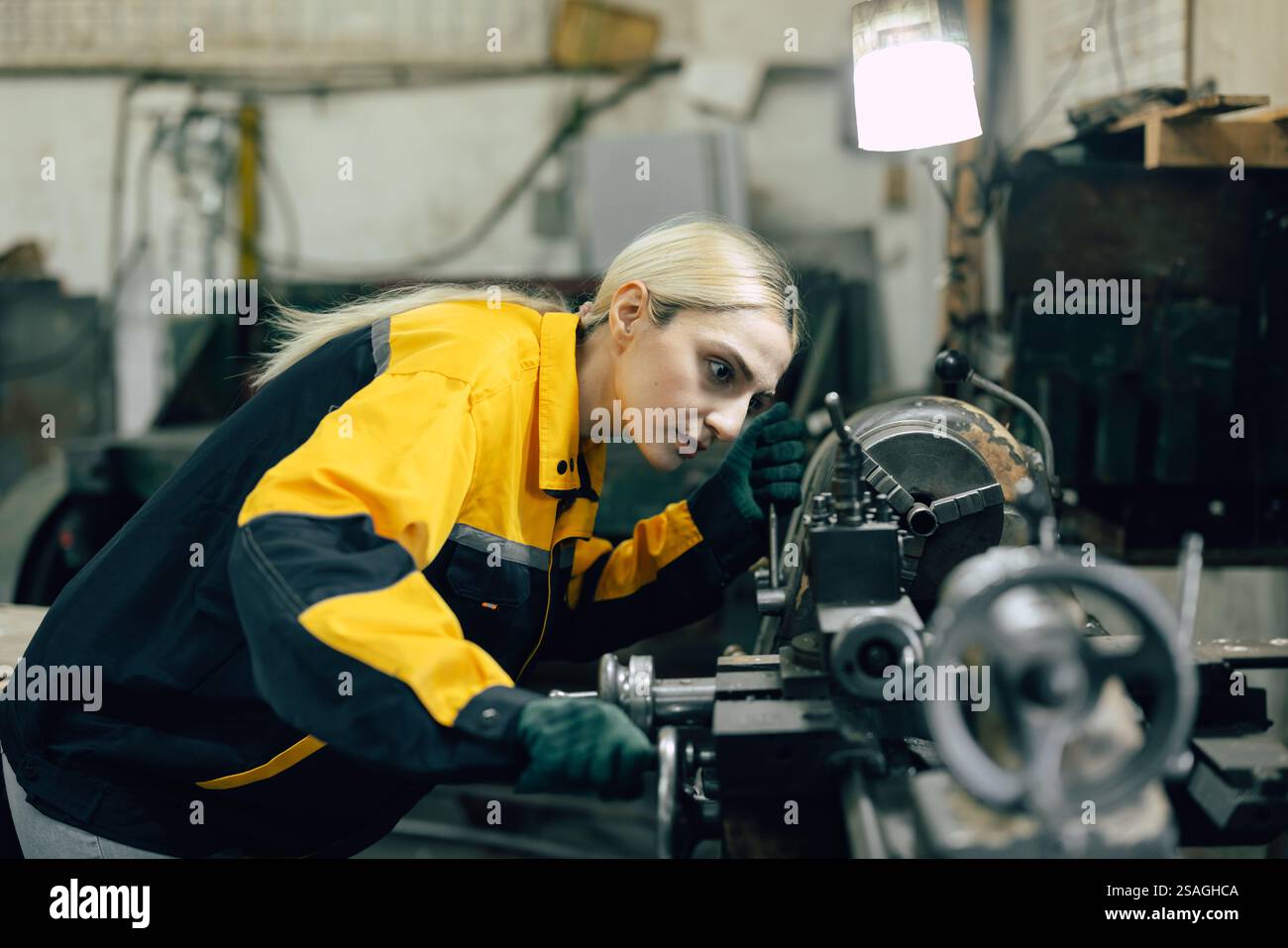 kaukasische Frauen arbeiten in einer Fabrik der Schwermetallindustrie mit einer Drehmaschine aus Stahl Stockfoto