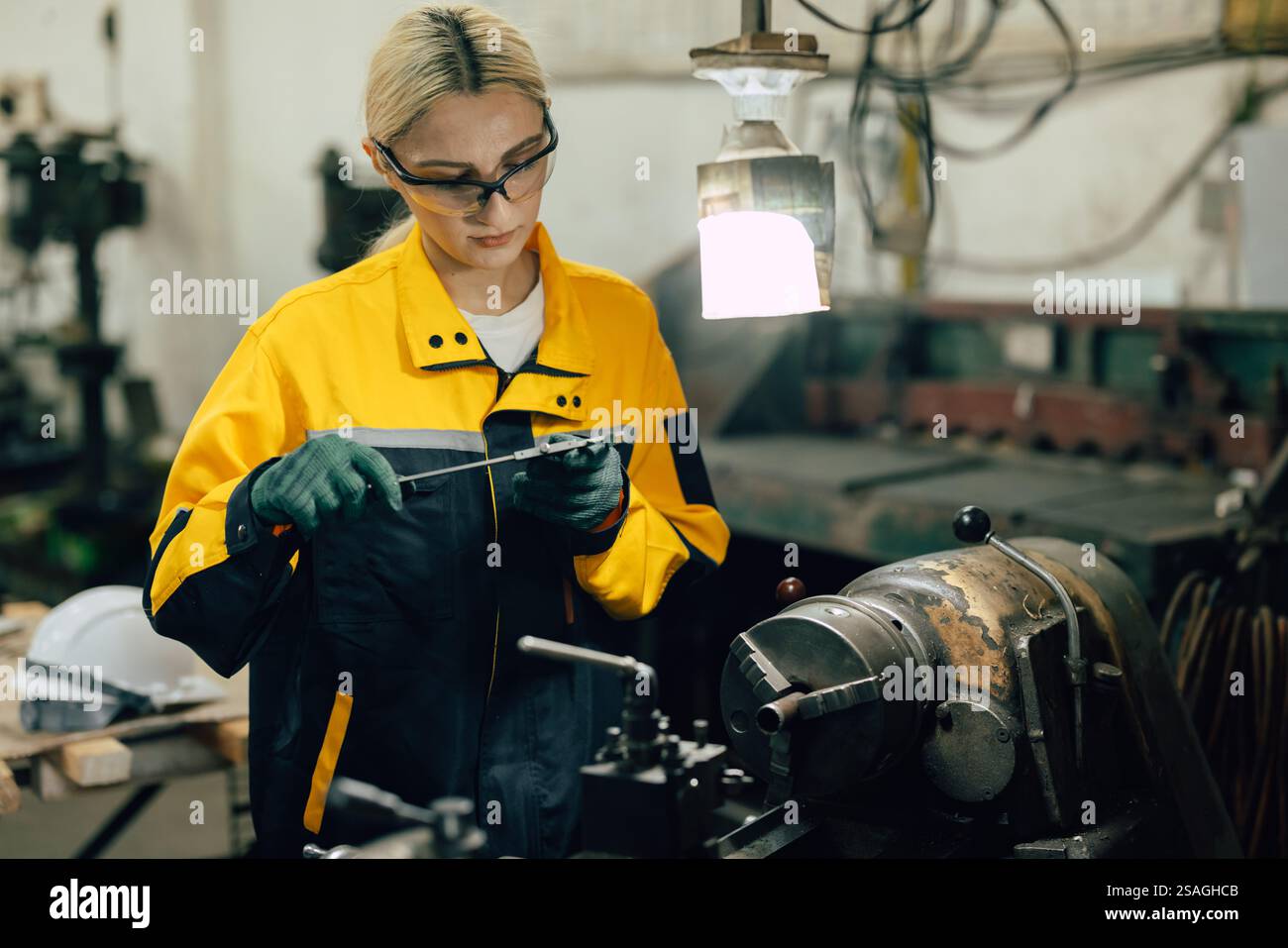 Arbeitnehmerin mit Messschieber zum Messen von Metallteilen in Drehmaschinen in der Schwermetallwerkstatt Stockfoto