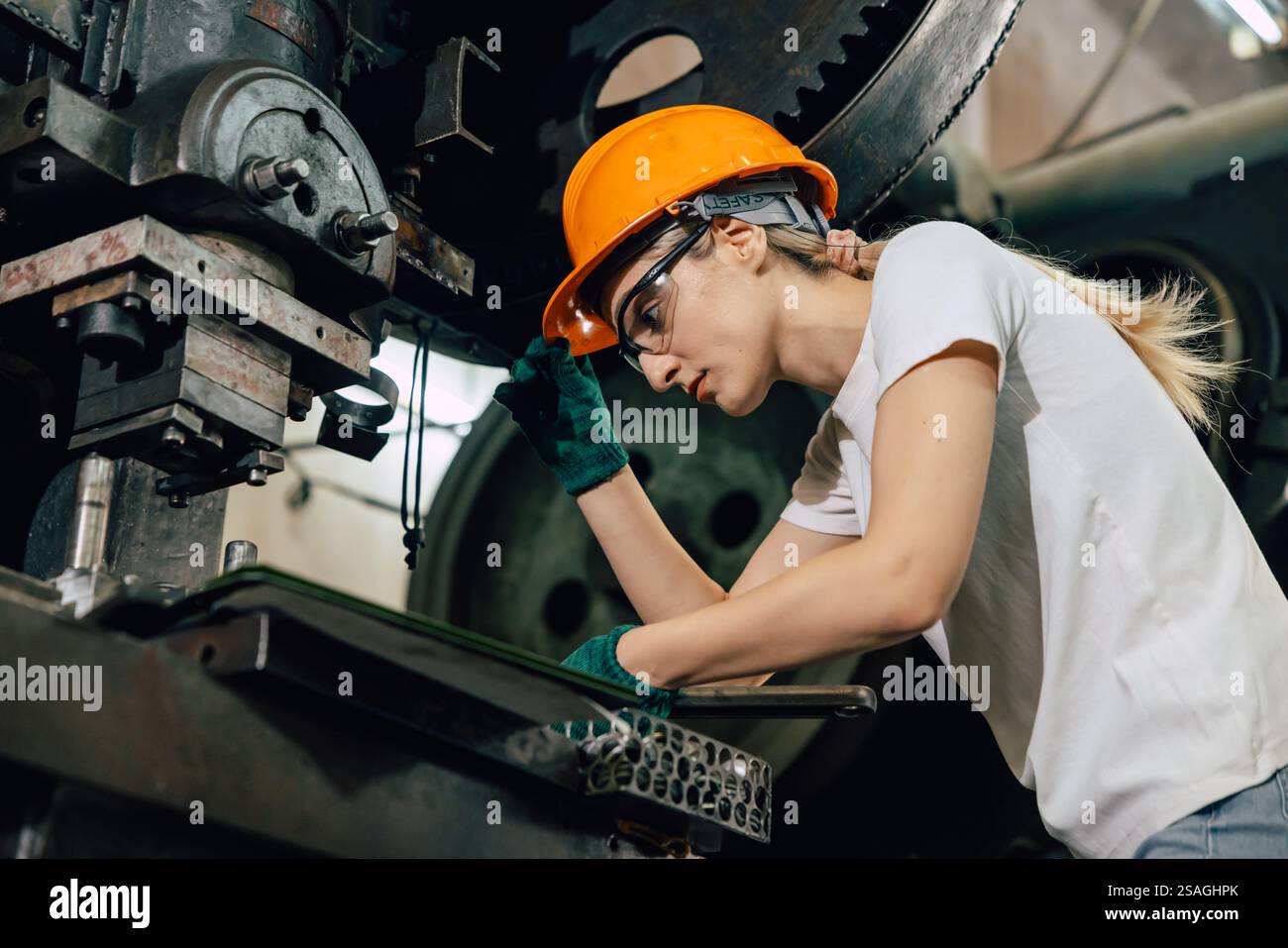 Weiblicher Techniker, der in der Schwerindustrie arbeitet, Fabrik Reparieren Service Wartung alte Maschine mit Sicherheit Stockfoto