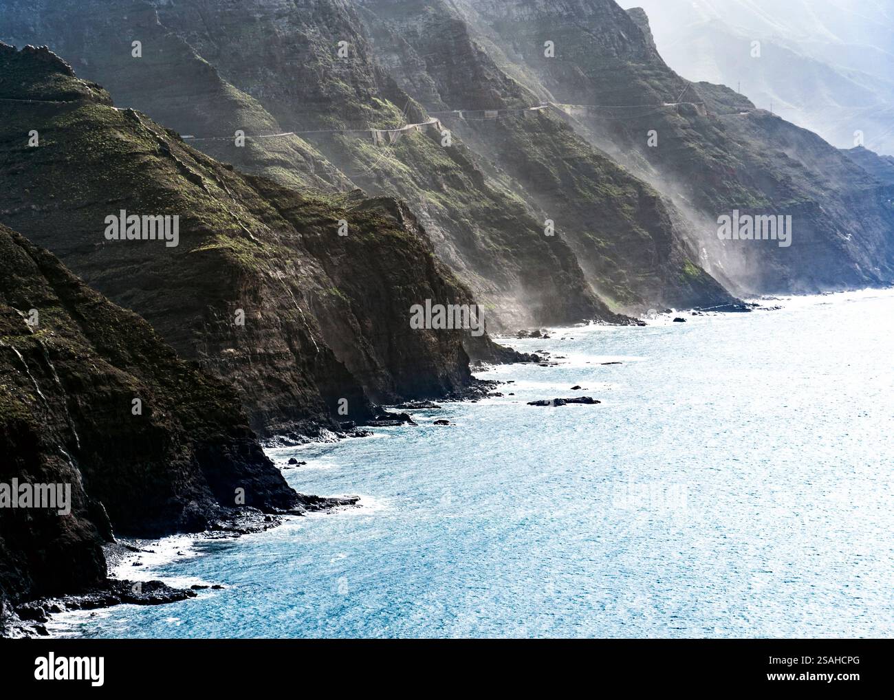 Ein atemberaubender Blick auf die Küste mit steilen Klippen und einem ruhigen Meer. Das Sonnenlicht erzeugt einen nebeligen Effekt über der Landschaft und unterstreicht die natürliche Schönheit Stockfoto