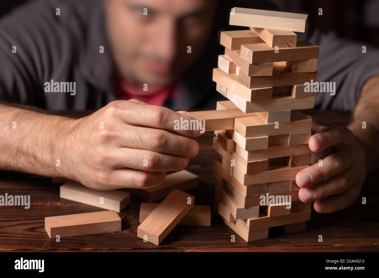 Man händet einen Stapel Holzblöcke für das Spiel auf einem dunkelbraunen Tisch, während man während der Quarantäne zu Hause bleibt, Familienaktivitäten zu Hause, Partybrett offline Stockfoto