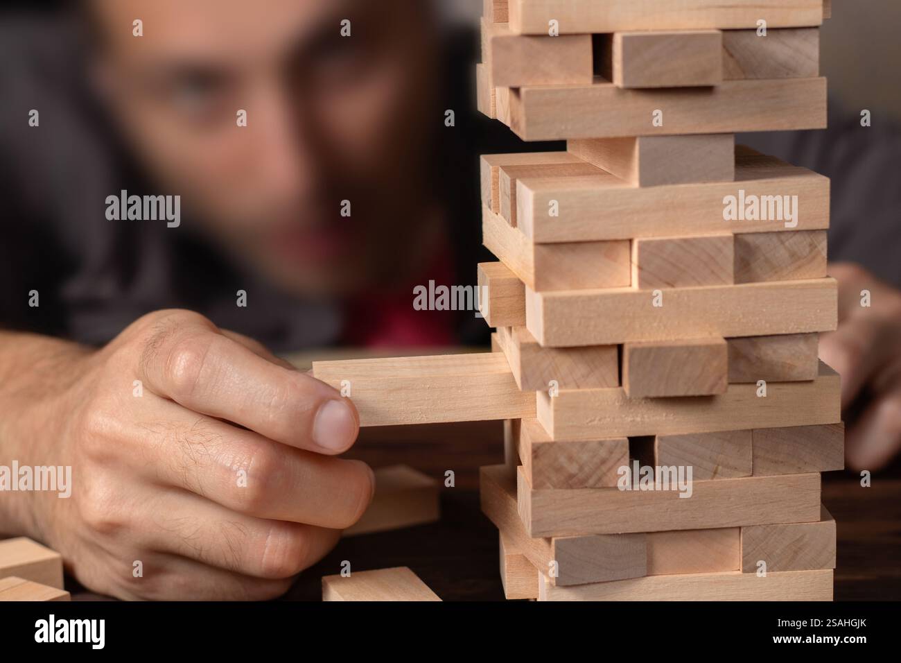 Man händet einen Stapel Holzblöcke für das Spiel auf einem dunkelbraunen Tisch, während man während der Quarantäne zu Hause bleibt, Familienaktivitäten zu Hause, Partybrett offline Stockfoto