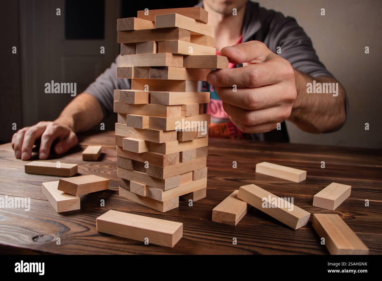 Man händet einen Stapel Holzblöcke für das Spiel auf einem dunkelbraunen Tisch, während man während der Quarantäne zu Hause bleibt, Familienaktivitäten zu Hause, Partybrett offline Stockfoto