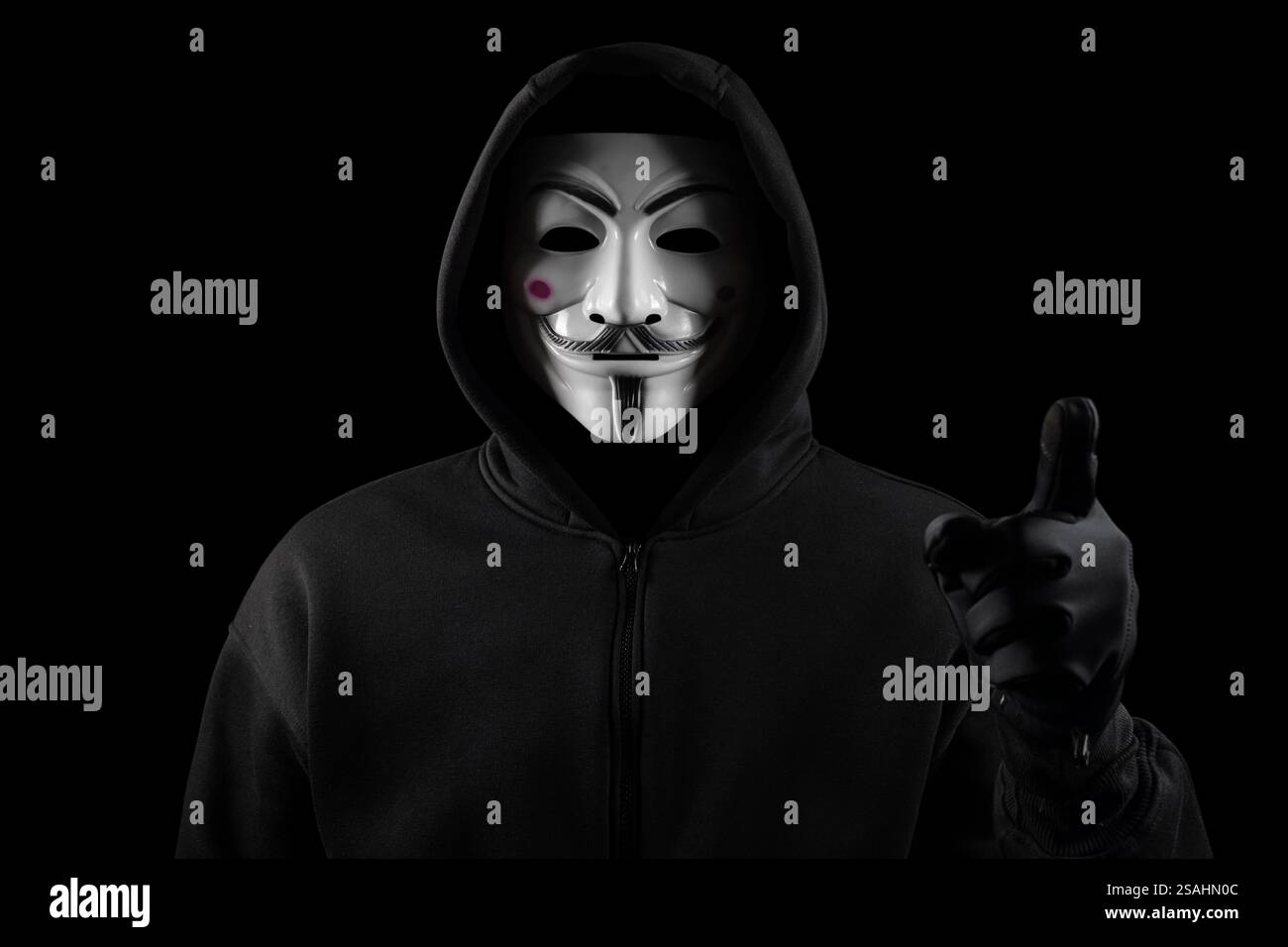 Dnipro. Ukraine 31 januar 2024: Mann mit anonymer Maske mit Sweatshirt in Handschuhen, Blick in die Kamera und Zeigefinger Stockfoto