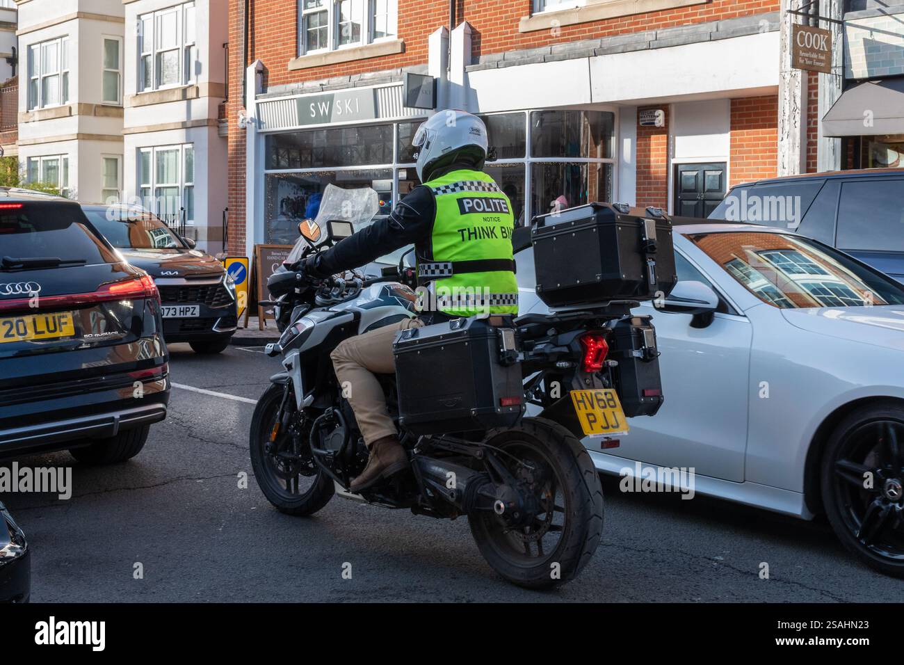 Motorradfahrer auf der belebten Straße in London mit einer hochsichtbaren Weste mit höflichem Hinweis Think Bike Safety Message, England, Großbritannien Stockfoto