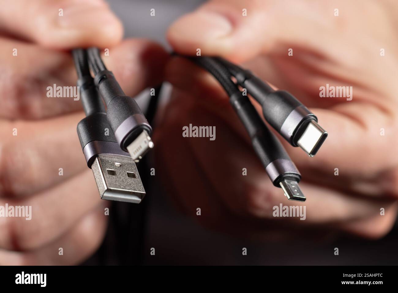 Hände halten das Universal-Adapterkabel von USB-Anschluss zu Micro-USB-, Mini-USB- und anderen Anschlüssen. Stockfoto