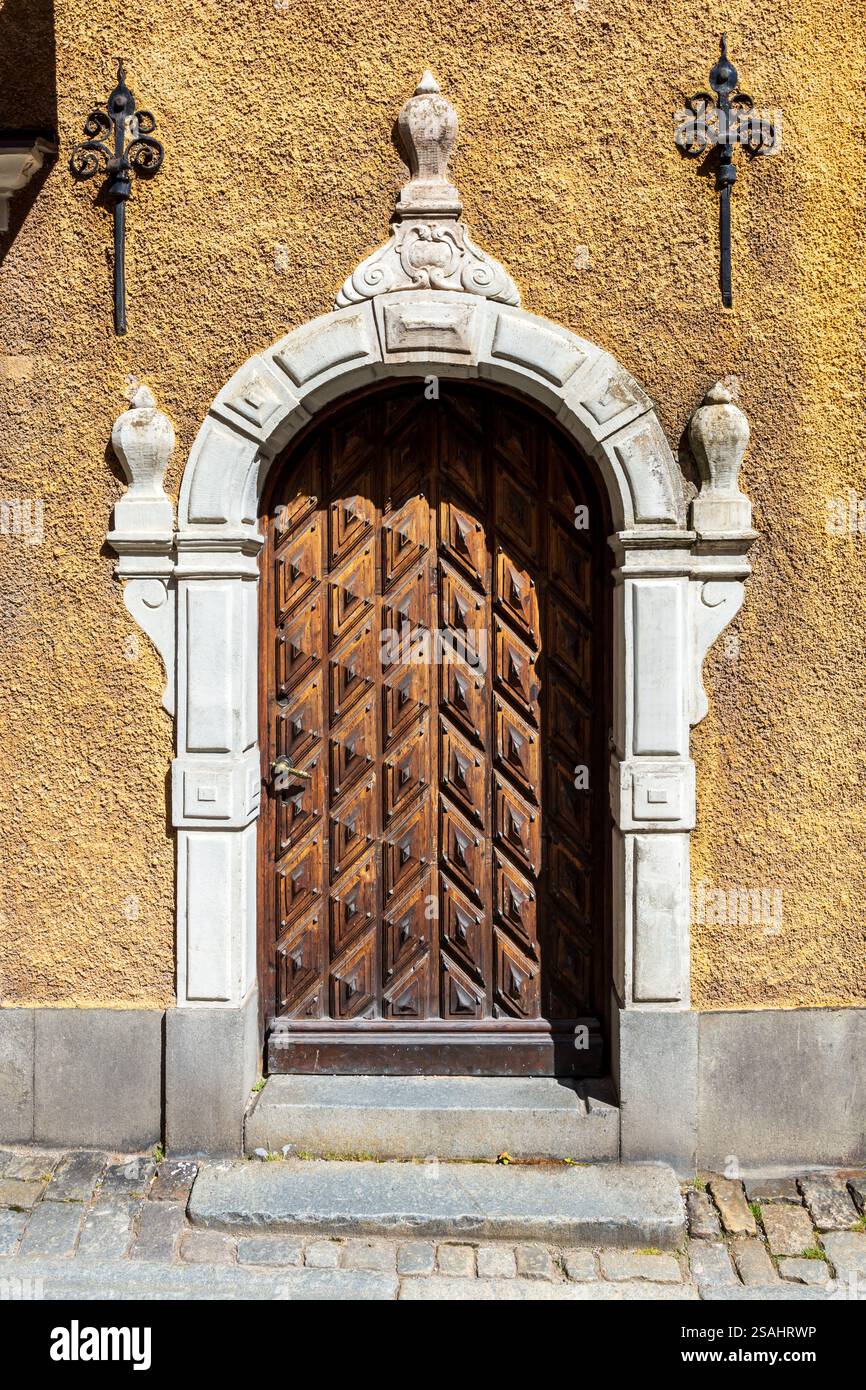 Vorderansicht der geschnitzten hölzernen Eingangstür eines mittelalterlichen Stadthauses in einer Kopfsteinpflasterstraße der Altstadt von Stockholm, Schweden. Stockfoto