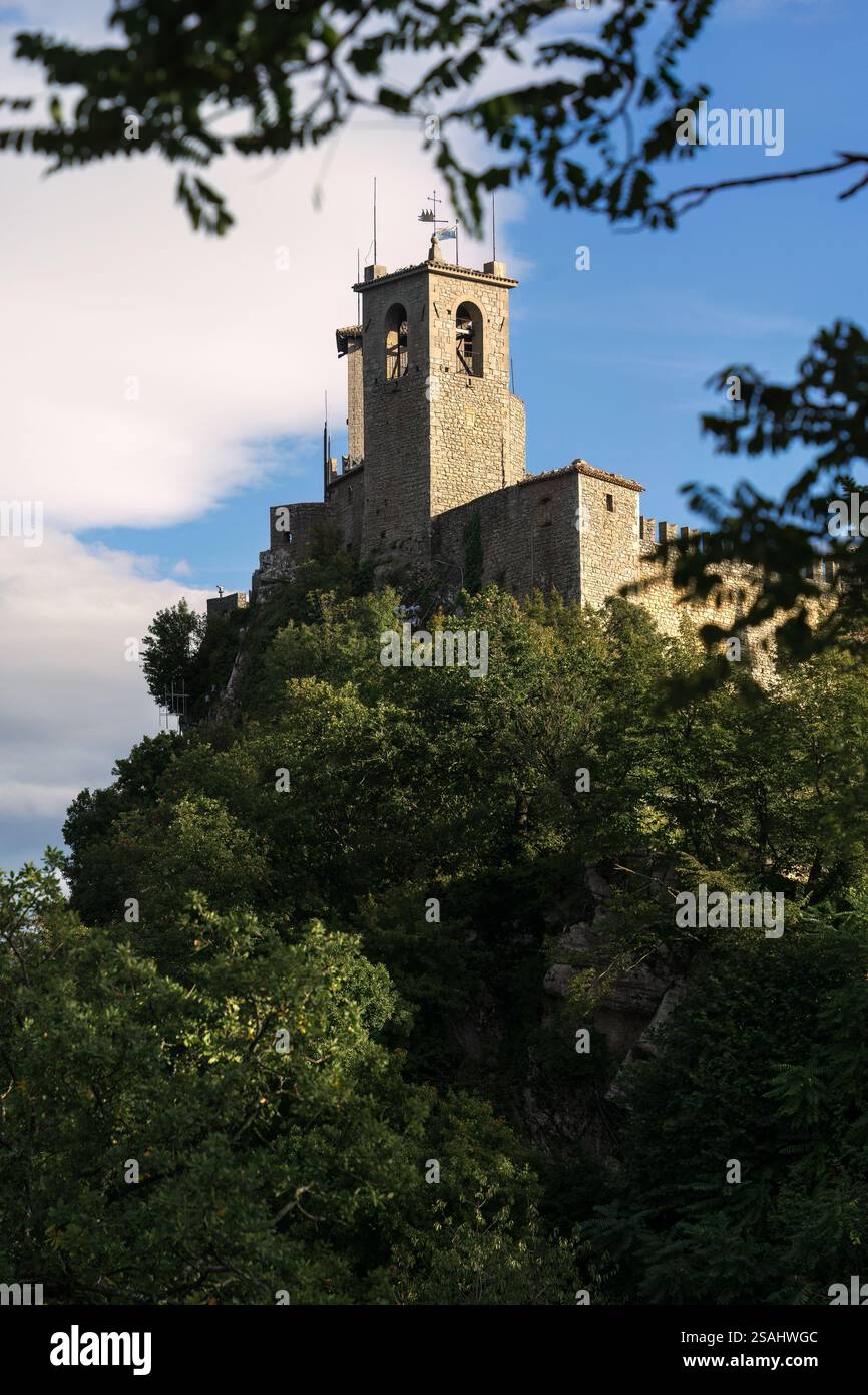 Alte Steinburg auf einem Hügel, umgeben von grünen Bäumen in San Marino Stockfoto