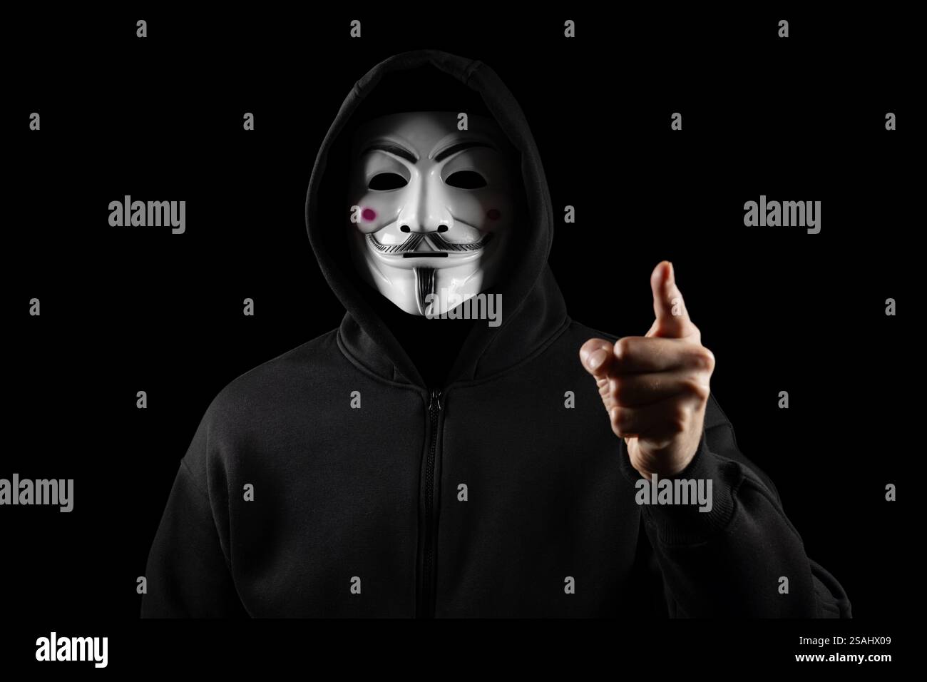 Dnipro. Ukraine 31 januar 2024: Mann mit anonymer Maske mit Sweatshirt, Blick in die Kamera und Zeigefinger, Studio-Aufnahme, Stockfoto