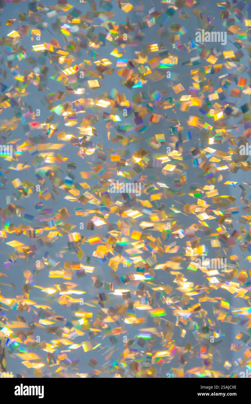 Glitzereffekt mit kleinen bunten Partikeln auf gedämpftem Hintergrund, Unschärfe Stockfoto