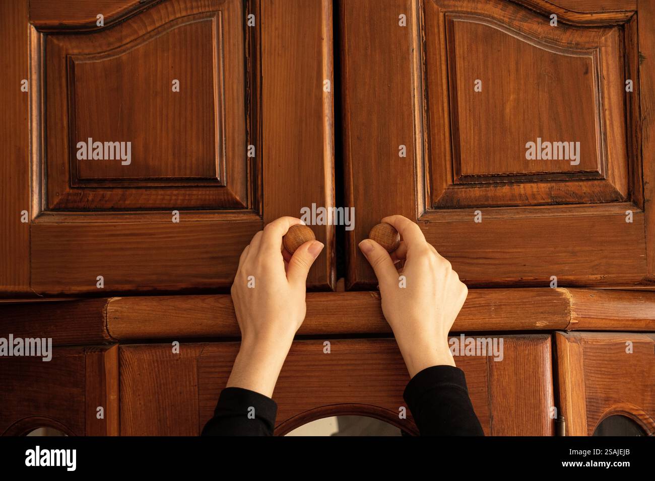 Frau Hand öffnet alten Holzschrank im Schlafzimmer zu Hause, alte Möbel Stockfoto