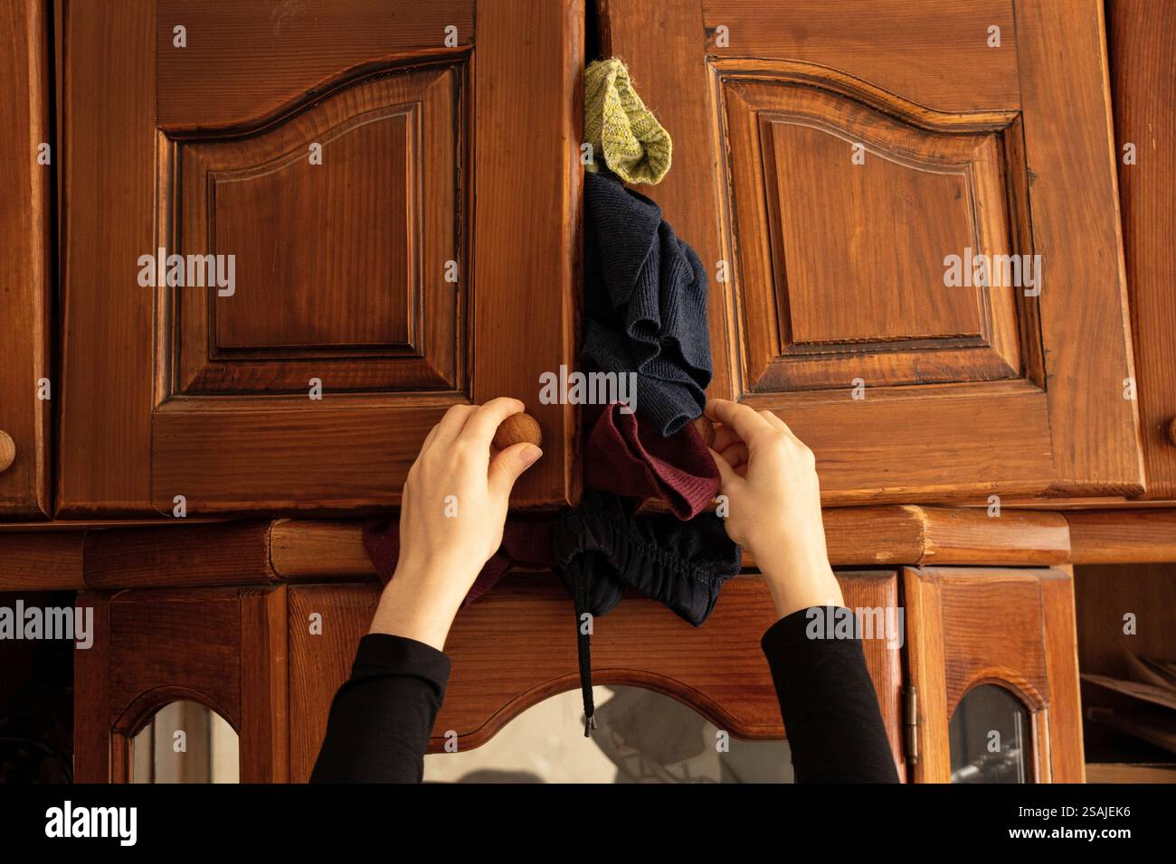 Das Mädchen schließt einen alten Schrank, aus dem Dinge rausfallen, Regal, viele Dinge, Hausreinigung Stockfoto