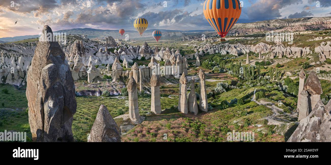 Heißluftballons fliegen Touristen über die spektakulären weltberühmten Felsformationen des „Love Valley“ bei Sonnenaufgang, in der Nähe von Goreme, Kappadokien, Türkei. Stockfoto