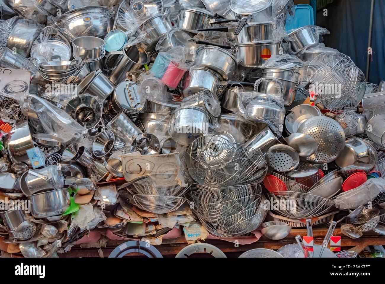 Ein riesiger Stapel von Küchenutensilien, Töpfen, Pfannen und Zubehör, die nach dem Zufallsprinzip aufeinander gestapelt werden, damit Kunden auswählen können. Stockfoto