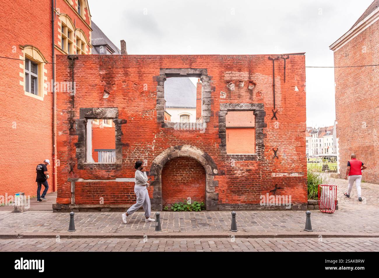 Historische Fassade aus rotem Backstein, die entlang einer kopfsteingepflasterten Straße in einer europäischen Stadt übrig geblieben ist Stockfoto