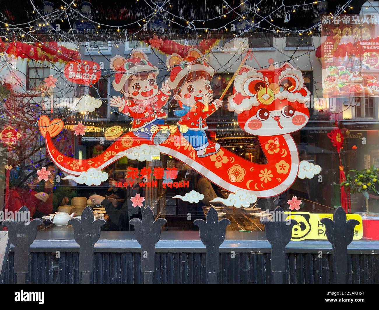 Dekoration in chinesischem Restaurant-Fenster, das das Jahr der Schlange feiert, Gerrard Street, London, Großbritannien - Smartphone-aufgenommenes Stockfoto