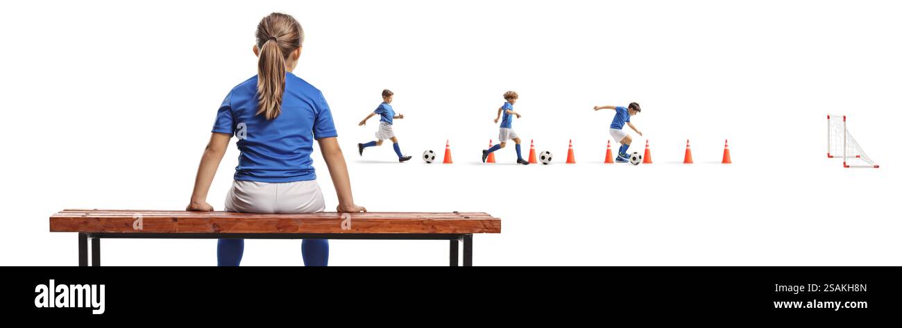 Mädchen, das auf einer Bank sitzt und Jungen beobachtet, die Fußball trainieren, isoliert auf weißem Hintergrund Stockfoto